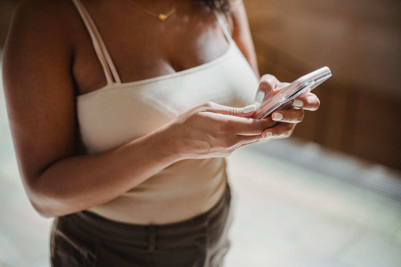 Close-up of a young woman using a smartphone indoors, showcasing modern lifestyle and connectivity.